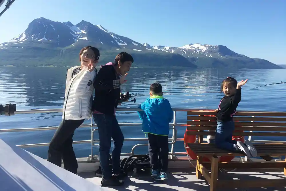 Adults and children on boat with snow-capped mountain backdrop