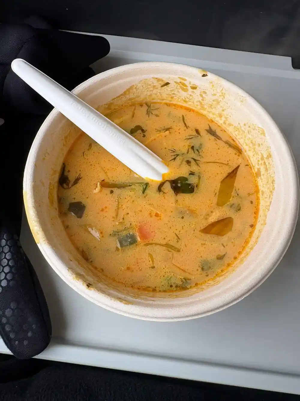 Bowl of creamy soup with herbs and white spoon