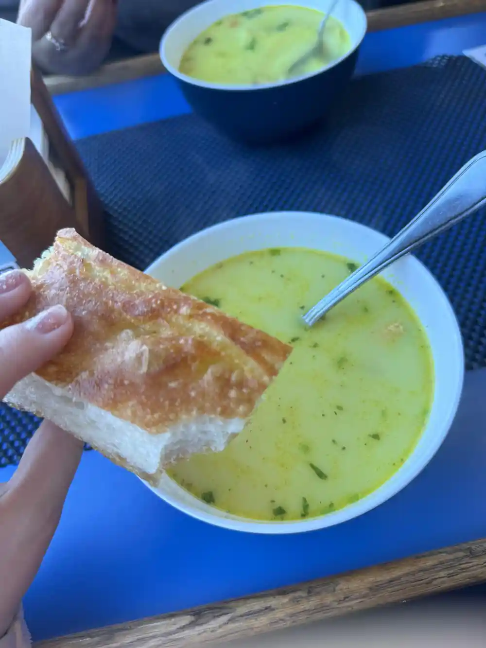 Green soup with bread served on blue table