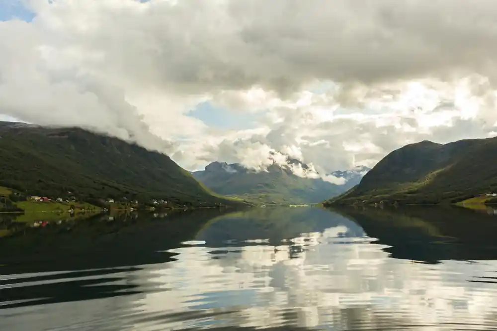 Green valley with steep mountains and reflective water