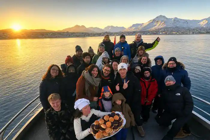 Large group holding platter of food outdoors on ice