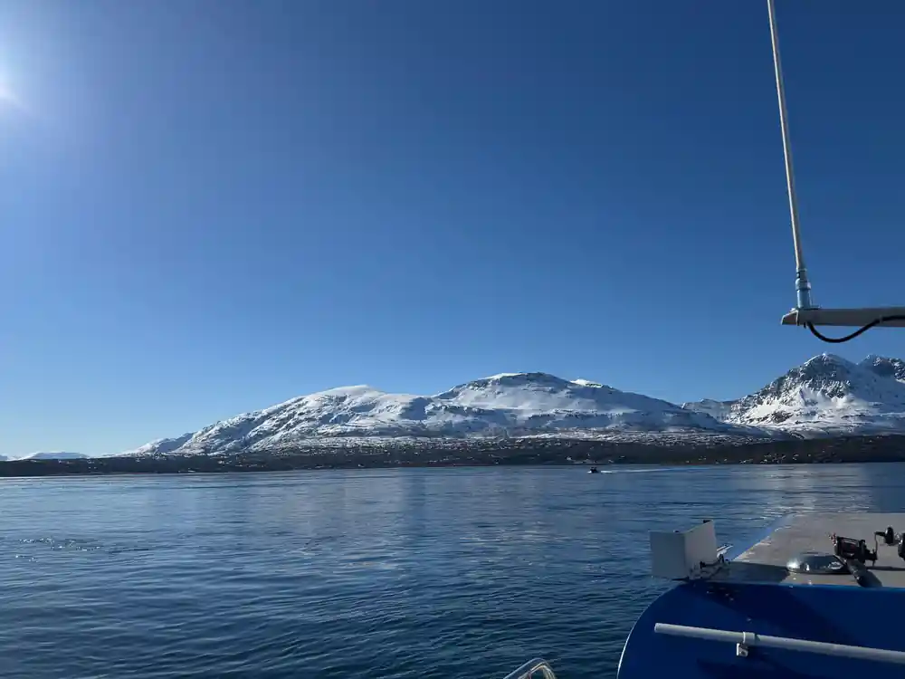 Snow-capped mountain across blue lake from boat