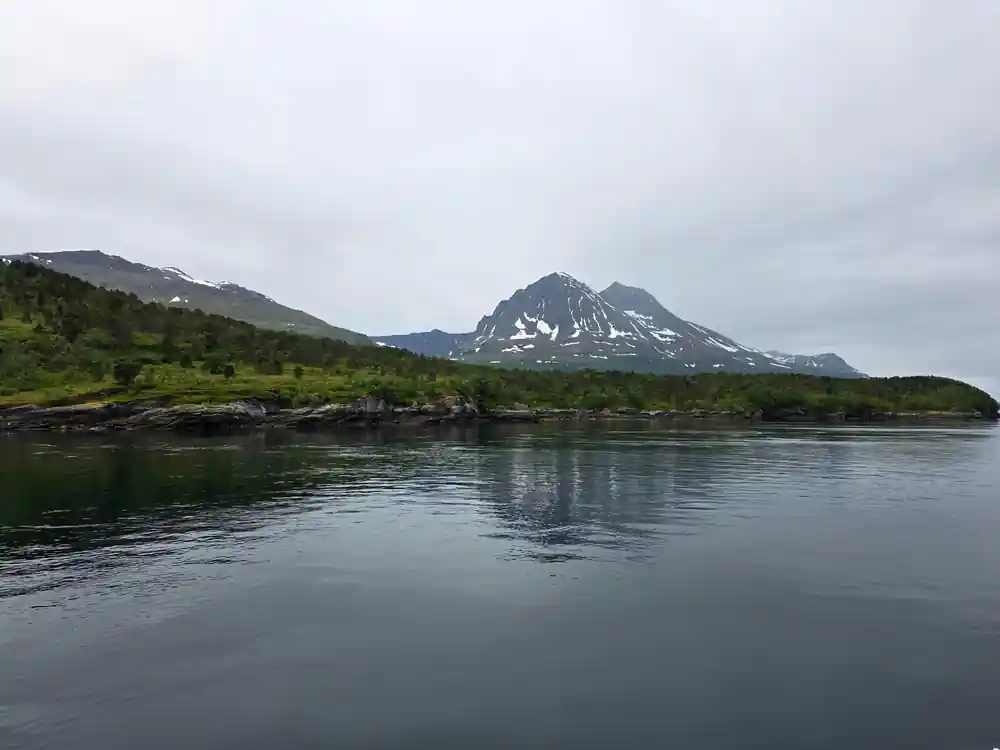 Snow-capped volcanic mountain across calm water