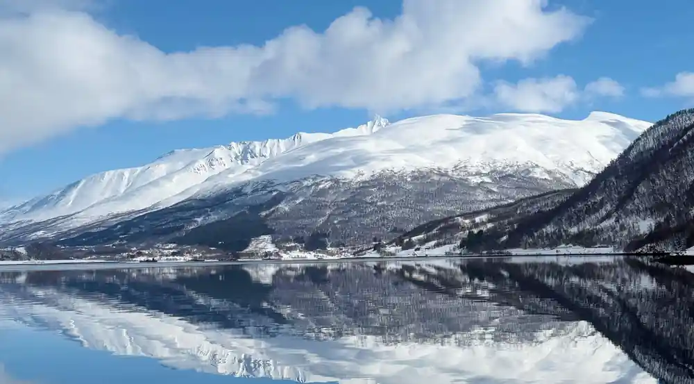 Snow-covered mountain reflected in still lake water
