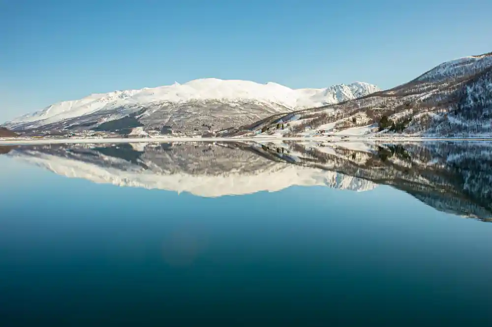 Snow-covered mountain reflected in still lake