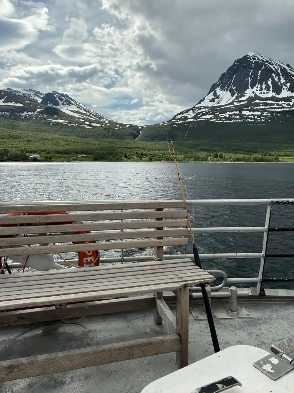 Snowy mountains across lake from boat railings