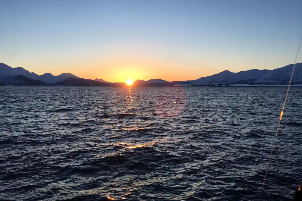 Sunset over calm water with snow-covered mountains