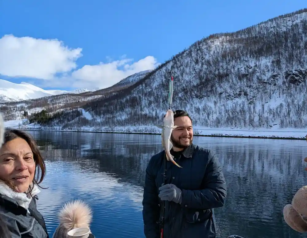 Two people on boat smiling with mountains and water