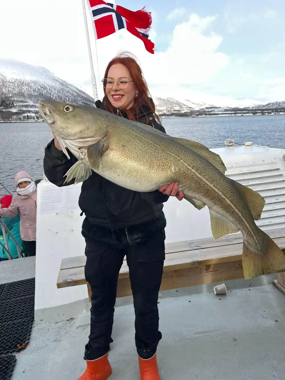Woman holding large fish with Norwegian flag and mountains