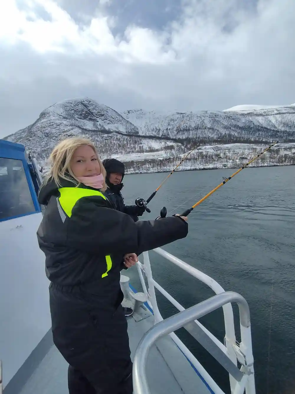 Woman in safety vest fishing on boat with mountains