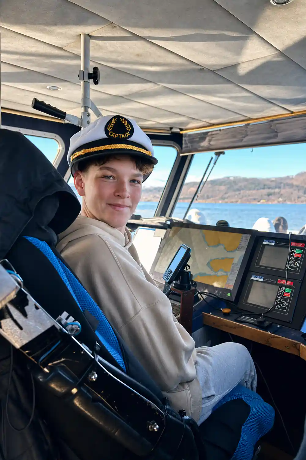 Young person at boat helm with mountain lake view
